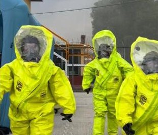 Equipo avanzando con trajes de protección química